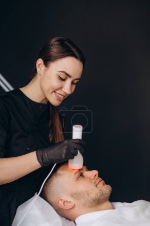 Photo for Young woman getting chromotherapy procedure for face skin rejuvenation. - Royalty Free Image
