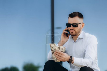 Téléchargez les photos : Homme d'affaires parler au téléphone et compter les dollars. - en image libre de droit
