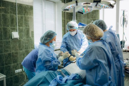 Foto de Cirujanos que perfeccionan la operación quirúrgica de la cesárea abdominal durante el parto en el quirófano de la clínica - Imagen libre de derechos