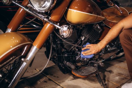 Foto de Un hombre limpia el motor de una motocicleta retro. Retro colector de coches y motocicletas. - Imagen libre de derechos