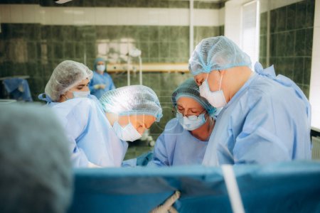 Photo for Surgeons perfoming surgery operation of abdominal cesarean section during child delivery birth at clinic operating room - Royalty Free Image