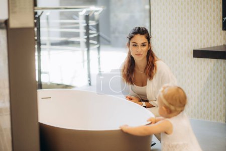 Téléchargez les photos : Mère et enfant acheter une baignoire dans la salle de bain. - en image libre de droit
