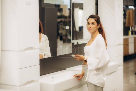 Foto de Una mujer en una tienda de espejos elige un espejo. - Imagen libre de derechos