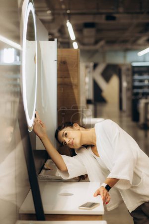 Foto de Una mujer en una tienda de espejos elige un espejo. - Imagen libre de derechos