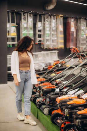 Photo for A woman buys a lawnmower in a store. High quality photo - Royalty Free Image