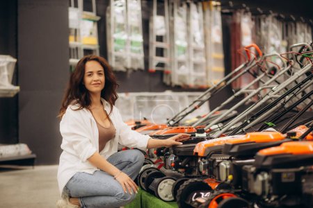 Photo for A woman buys a lawnmower in a store. High quality photo - Royalty Free Image