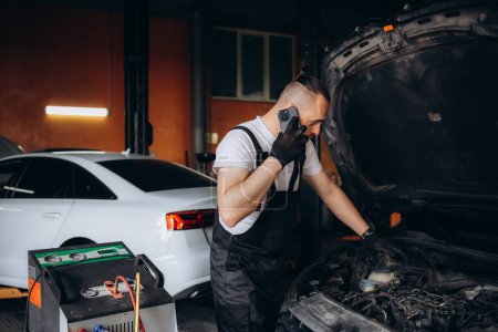 Photo for Male car mechanic filling up car air conditioner and check the compressor oil system caused by the car air conditioner is not cold. High quality photo - Royalty Free Image