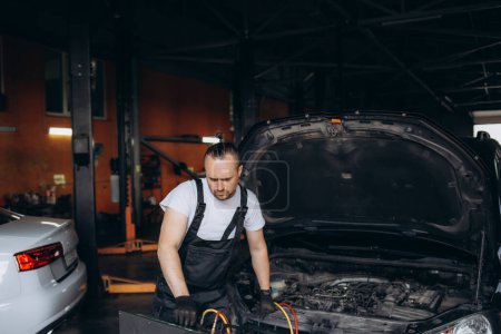 Photo for Male car mechanic filling up car air conditioner and check the compressor oil system caused by the car air conditioner is not cold. High quality photo - Royalty Free Image