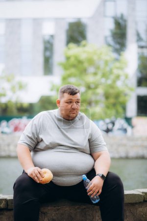 Photo for A very fat man is eating a burger - Royalty Free Image