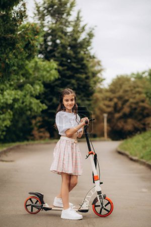 Photo for Little girl riding a kick scooter on a street near home. High quality photo - Royalty Free Image