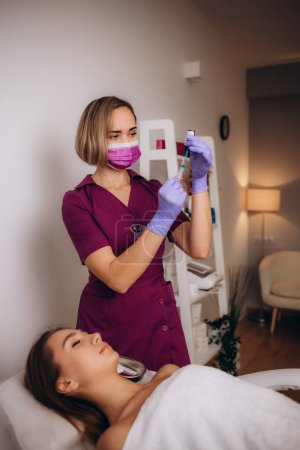 Photo for Brunette esthetician at the workplace with syringe in her hand. High quality photo - Royalty Free Image