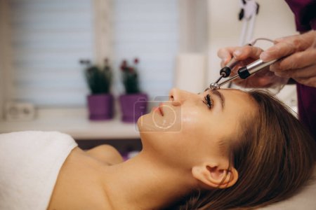 Photo for Woman getting microcurrent procedure facelift. Beautician doing anti-aging, to perform facial tightening and toning. High quality photo - Royalty Free Image