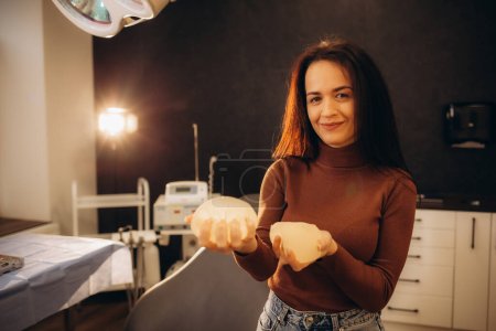 Téléchargez les photos : Main féminine serrant l'implant mammaire rond doux. Voie isolée et coupante. Photo de haute qualité - en image libre de droit