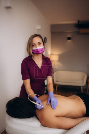 A beautician removes papillomas on a man's back. High quality photo
