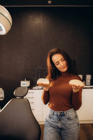 Téléchargez les photos : Une femme examine un implant mammaire dans le cabinet d'un médecin. - en image libre de droit