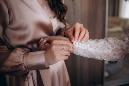 Téléchargez les photos : Mariée et mères mains aidant à mettre sur la robe de mariée. Photo de haute qualité - en image libre de droit