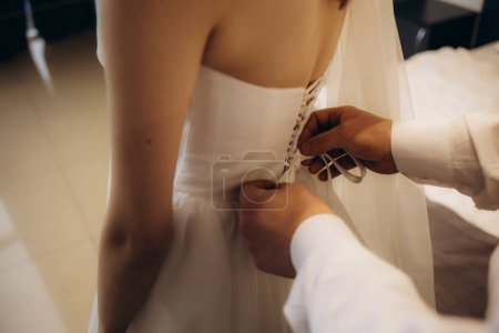 Téléchargez les photos : Mariée et mères mains aidant à mettre sur la robe de mariée. Photo de haute qualité - en image libre de droit