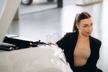 a woman looks at a car engine in a car dealership
