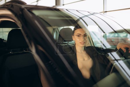 Happy woman driving a car and smiling. Cute young success happy brunette woman is driving a car. Portrait of happy female driver steering car with safety belt. High quality photo