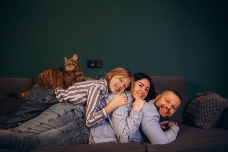 father, mother, daughter and. the cat is lying on the sofa