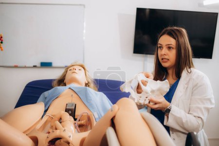Un obstetra-ginecólogo profesor muestra el parto de los estudiantes en un maniquí