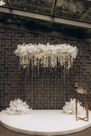 Schöne moderne sechseckige Hochzeitsbogen für einzigartige zeitgenössische Trauung mit frischem Grün und Lichtern und Kerzen. Hochwertiges Foto