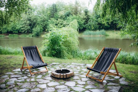 Dos sillas de madera en un muelle de madera con vistas a un lago al atardecer
