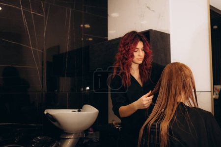 Hairstylist trimming hair of the customer in a beauty salon. High quality photo