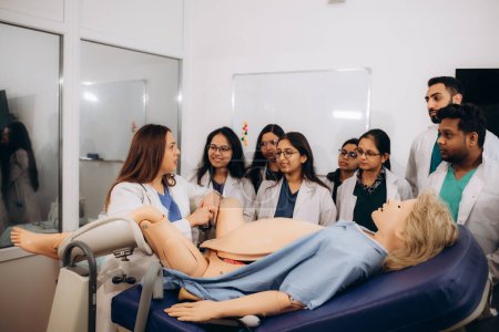 A group of medical students learn obstetrics by performing practical tasks on a mannequin