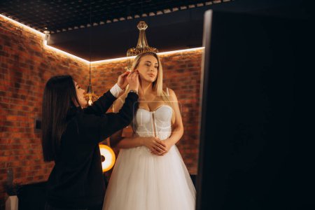 Photo for A consultant in a wedding salon helps the bride to put on a wedding dress - Royalty Free Image
