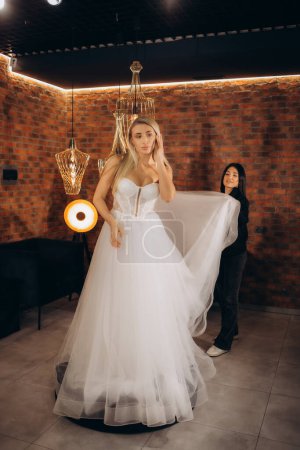 Téléchargez les photos : Belle mariée essayant sur une robe de mariée - en image libre de droit