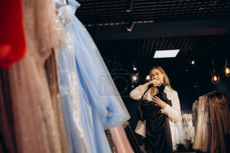 A beautiful woman chooses an evening dress in a store