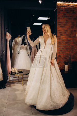 the bride takes a picture of herself in the mirror in the wedding salon