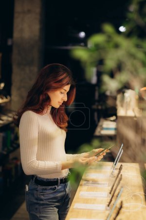 Side view of woman beaming while choosing phone cover. High quality photo