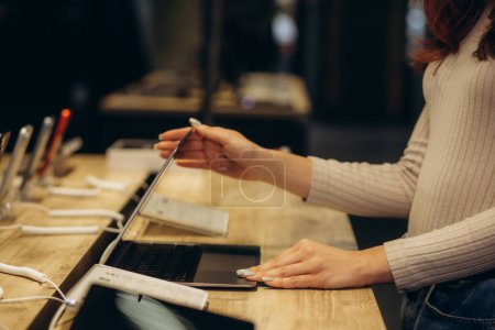 una mujer está buscando un portátil en una tienda de electrónica