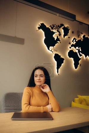 Photo for Female travel agent in the office on the background of the world map - Royalty Free Image