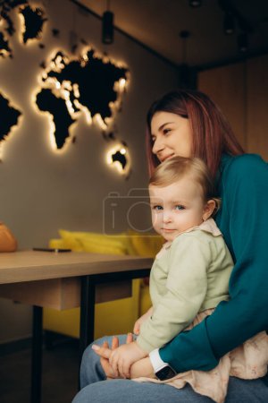 a little girl in her mother's arms in a travel agency