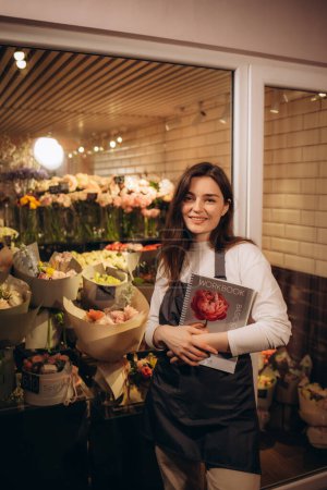 Foto de Florista femenina en una floristería con un cuaderno en sus manos - Imagen libre de derechos
