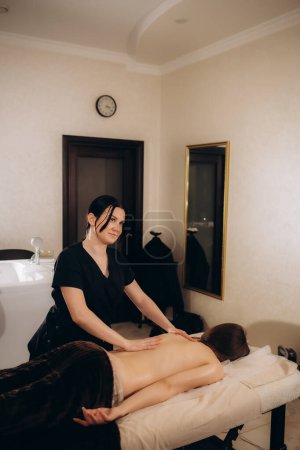 Téléchargez les photos : Masseur donnant massage profond du dos des tissus à la jeune cliente - en image libre de droit