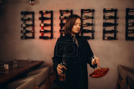 camarera de vino femenina sonriente sosteniendo el decantador en la tienda de vinos
