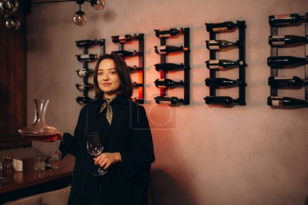 camarera de vino femenina sonriente sosteniendo el decantador en la tienda de vinos

