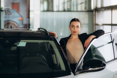 Femme concessionnaire de voitures debout dans le showroom
 