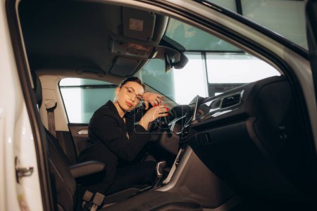 Téléchargez les photos : Une femme au milieu d'une voiture dans un concessionnaire automobile - en image libre de droit