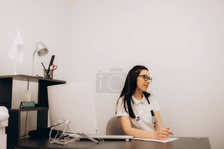 Portrait of adult female doctor sitting at desk in office clinic. Nurse gynecologist therapist general practitioner listening to patient. Telemedicine