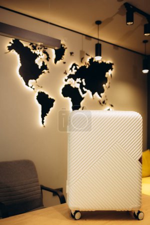 Une valise sur le fond d'une carte du monde en bois