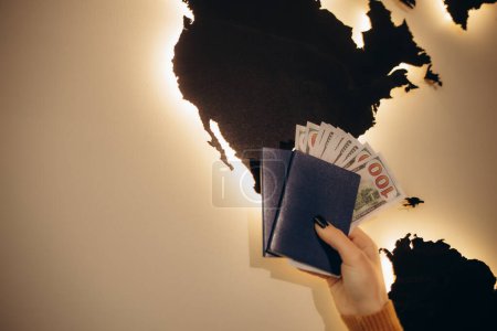 passeport avec dollars sur le fond d'une carte du monde en bois