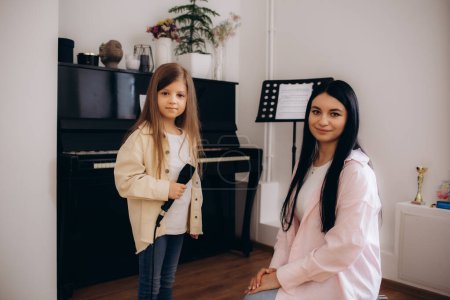 Vocal lesson. Girl in blue dress and her teacher doing voice exercises