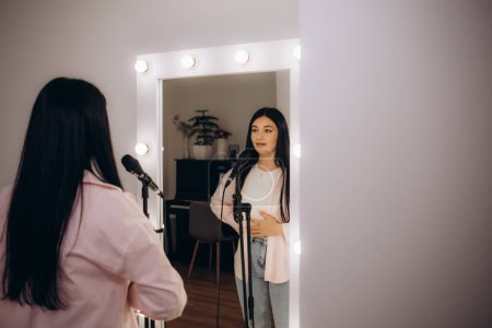woman reflection in the mirror sings into the microphone