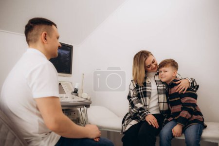 Médecin faisant une échographie à un enfant patient masculin au cabinet d'échographie de la clinique médicale. Diagnostic échographique de la glande thyroïde pour les enfants