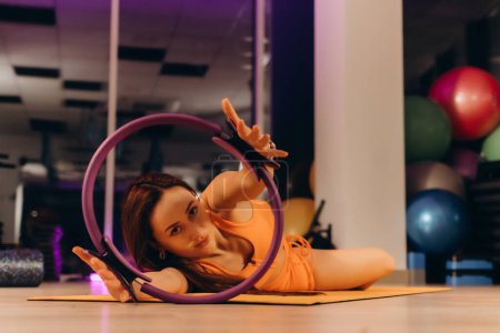 an athletic woman in the gym doing stretches with a circle